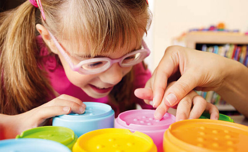 Fille avec des lunettes de vue touche à ses jouets.